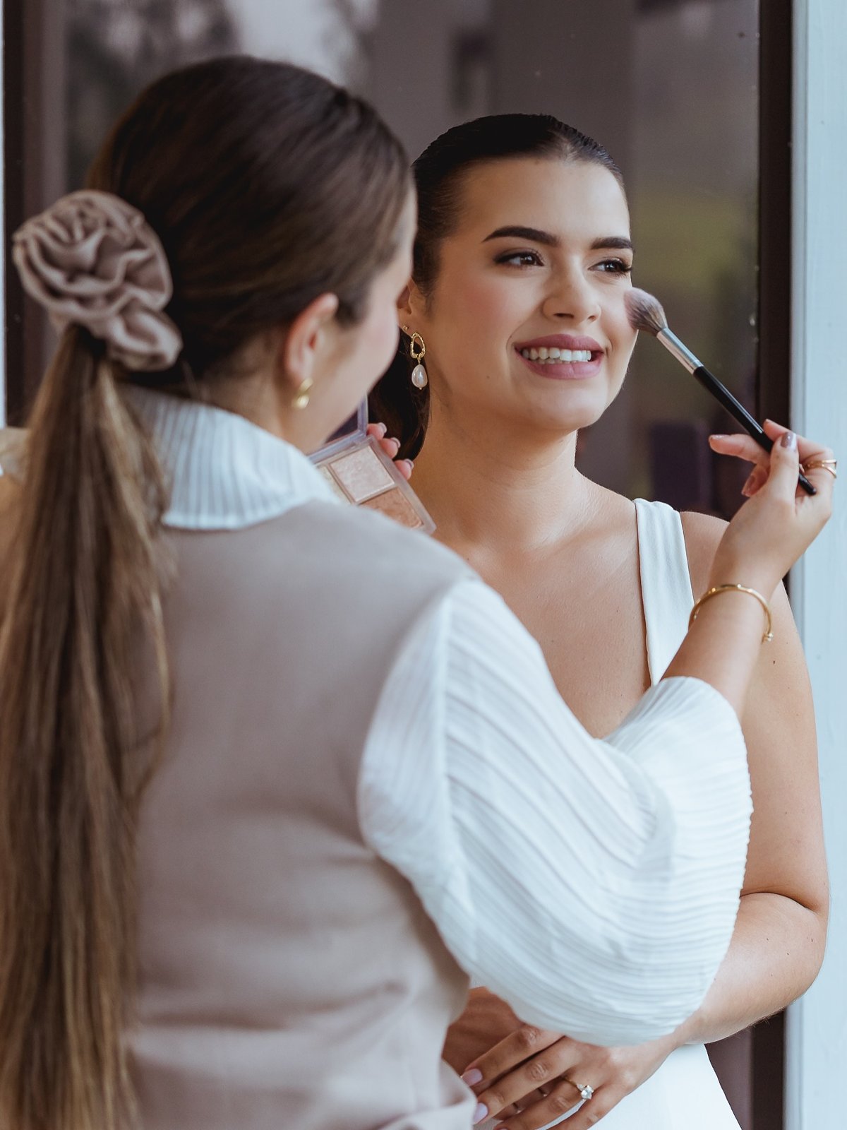 Maria Paula aplicando blush em uma noiva sorridente